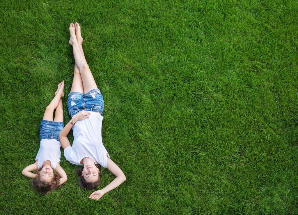 kids lay down on green lawn